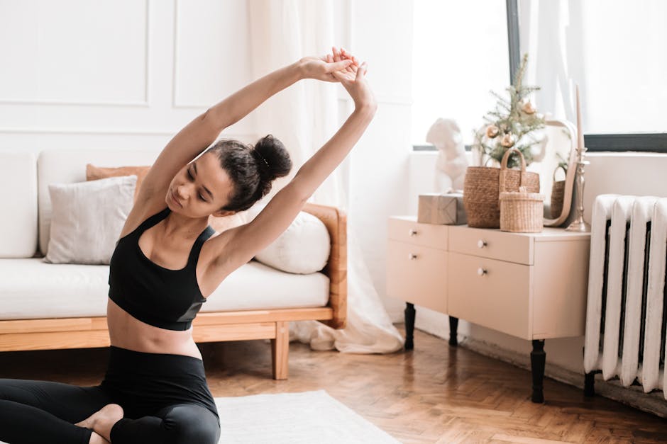 Person in a comfortable sitting pose meditating on a yoga mat in a sunlit room